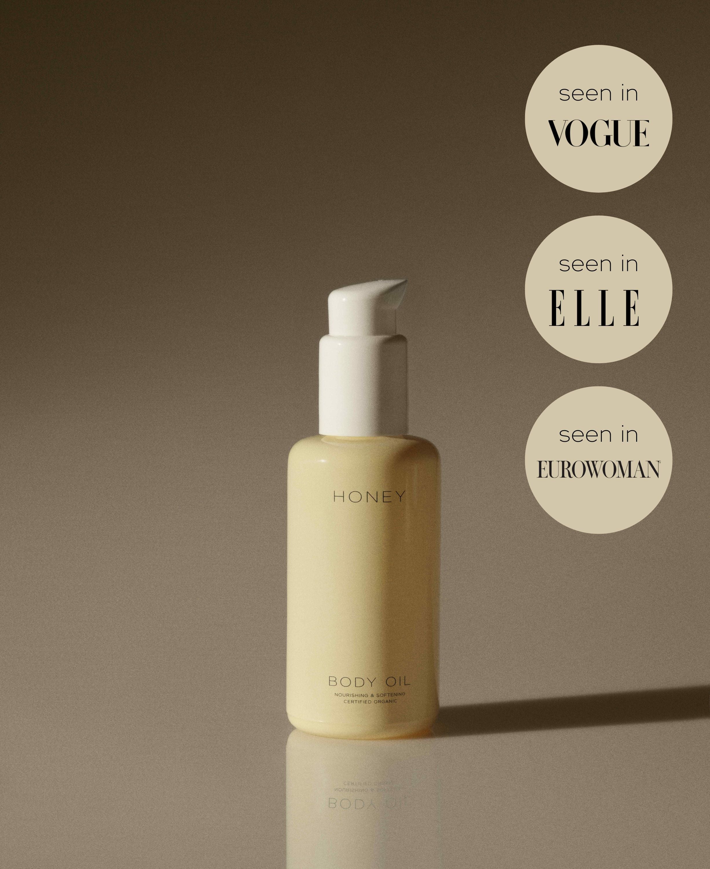 Natural fragrance-free body oil in yellow bottle with white cap and PR promotions about Vogue, Elle and Eurowoman