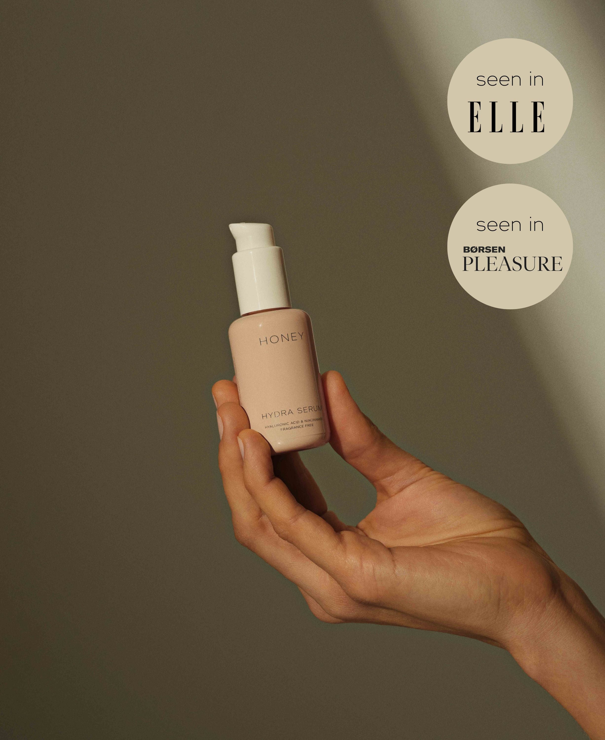 Hand holding natural fragrance-free hydra serum in dusty pink bottle with white cap