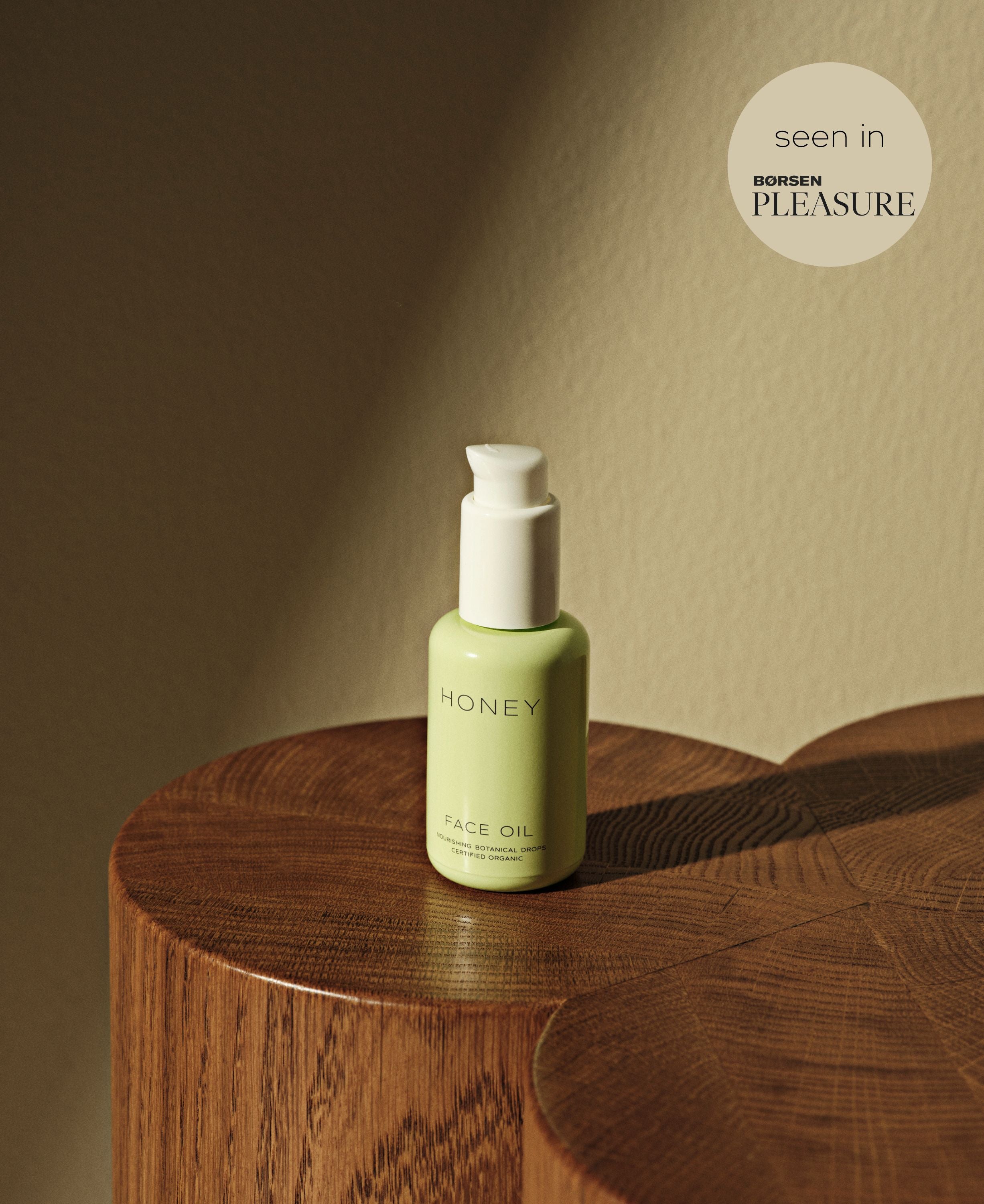 Natural clean skincare face oil in green bottle with white cap standing on wooden table