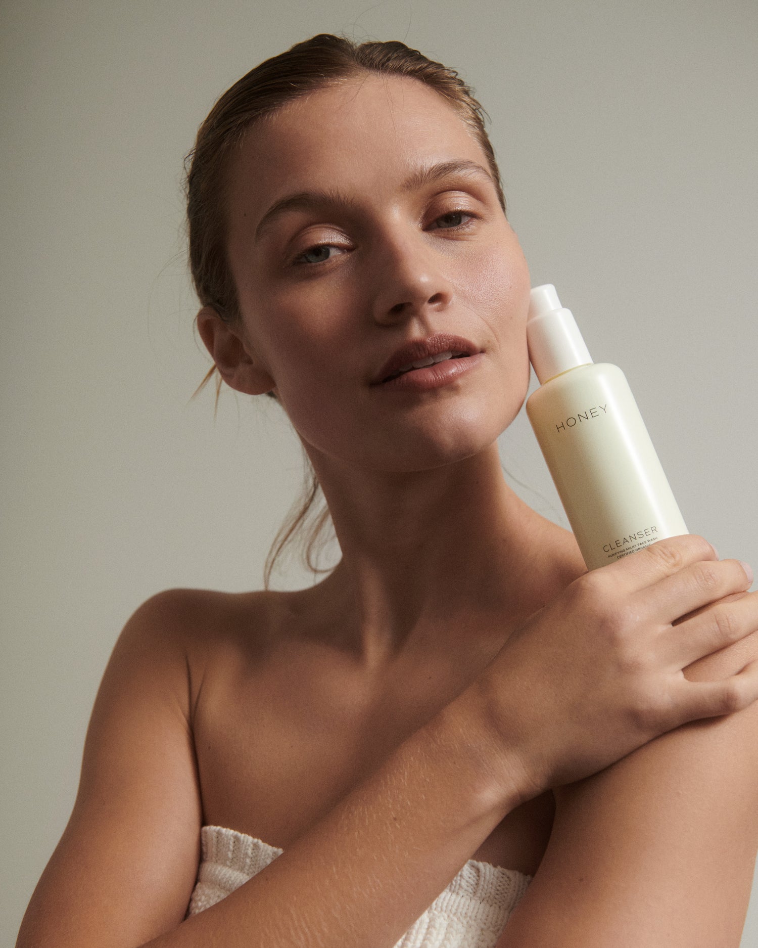 Woman holding natural clean skincare cleanser - face wash in light yellow bottle with white cap