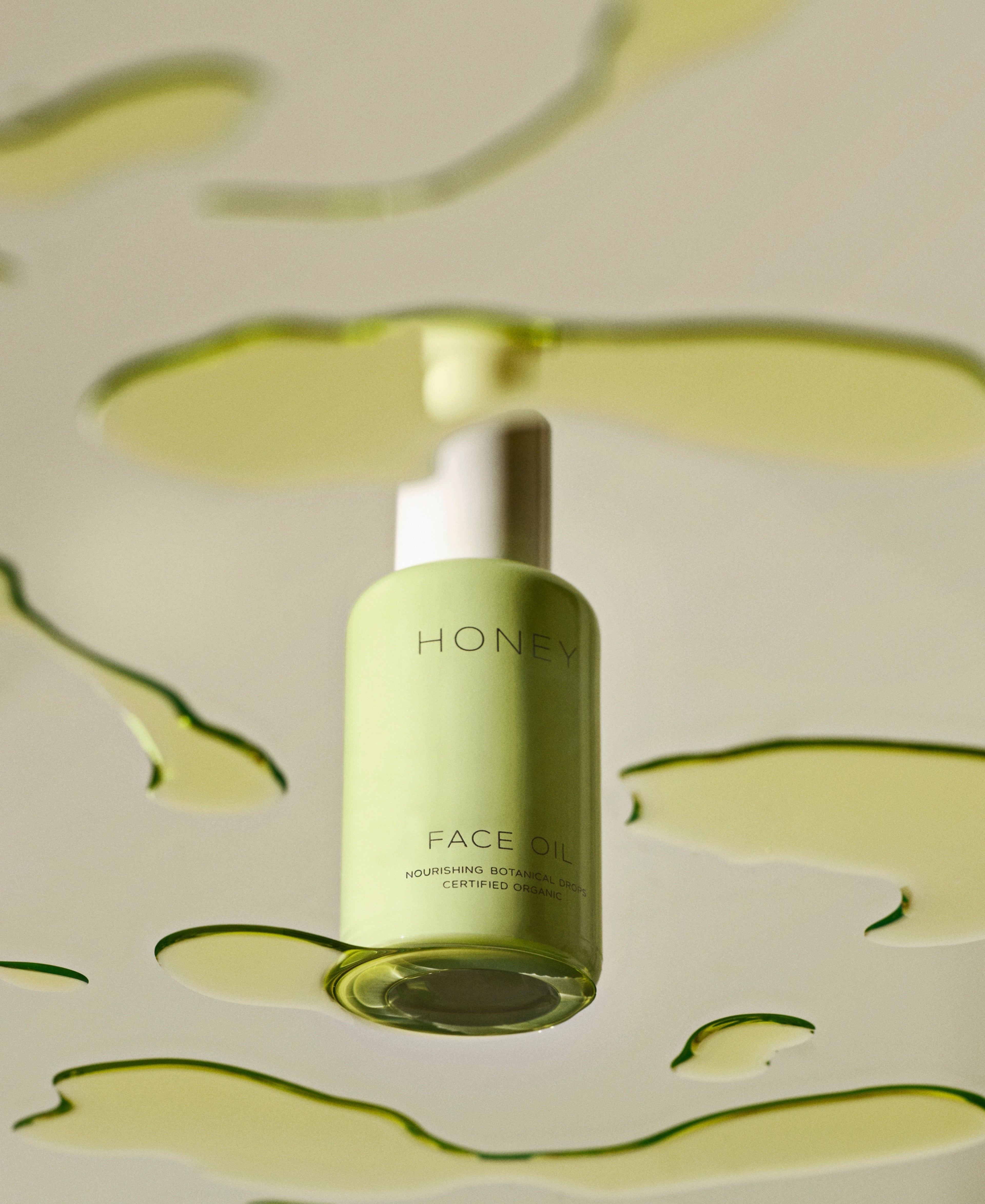 Natural fragrance-free face oil in green bottle with white cap with green botanical drops on table