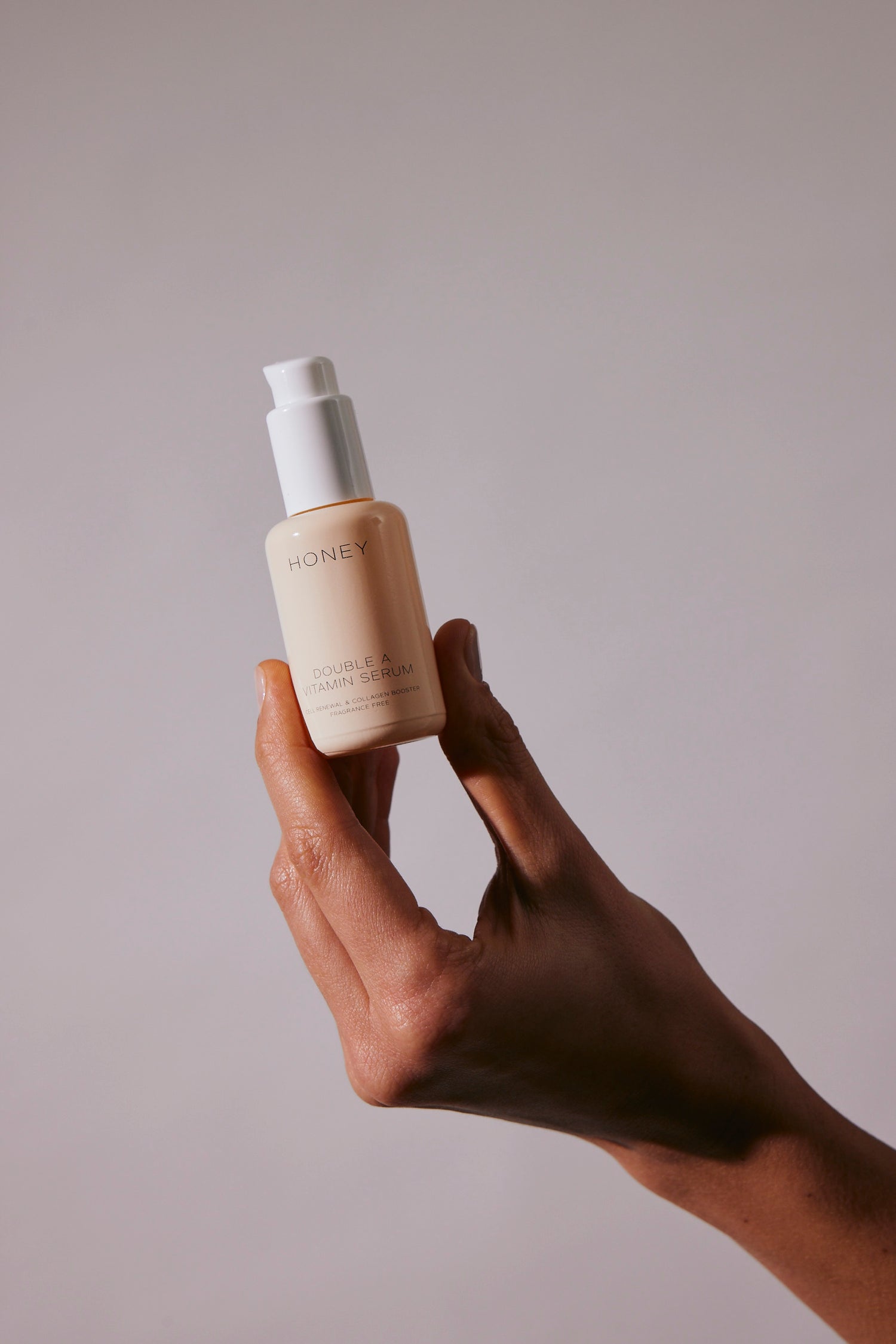 Hand holding double A vitamin serum in light pink bottle with white cap - natural and clean skincare