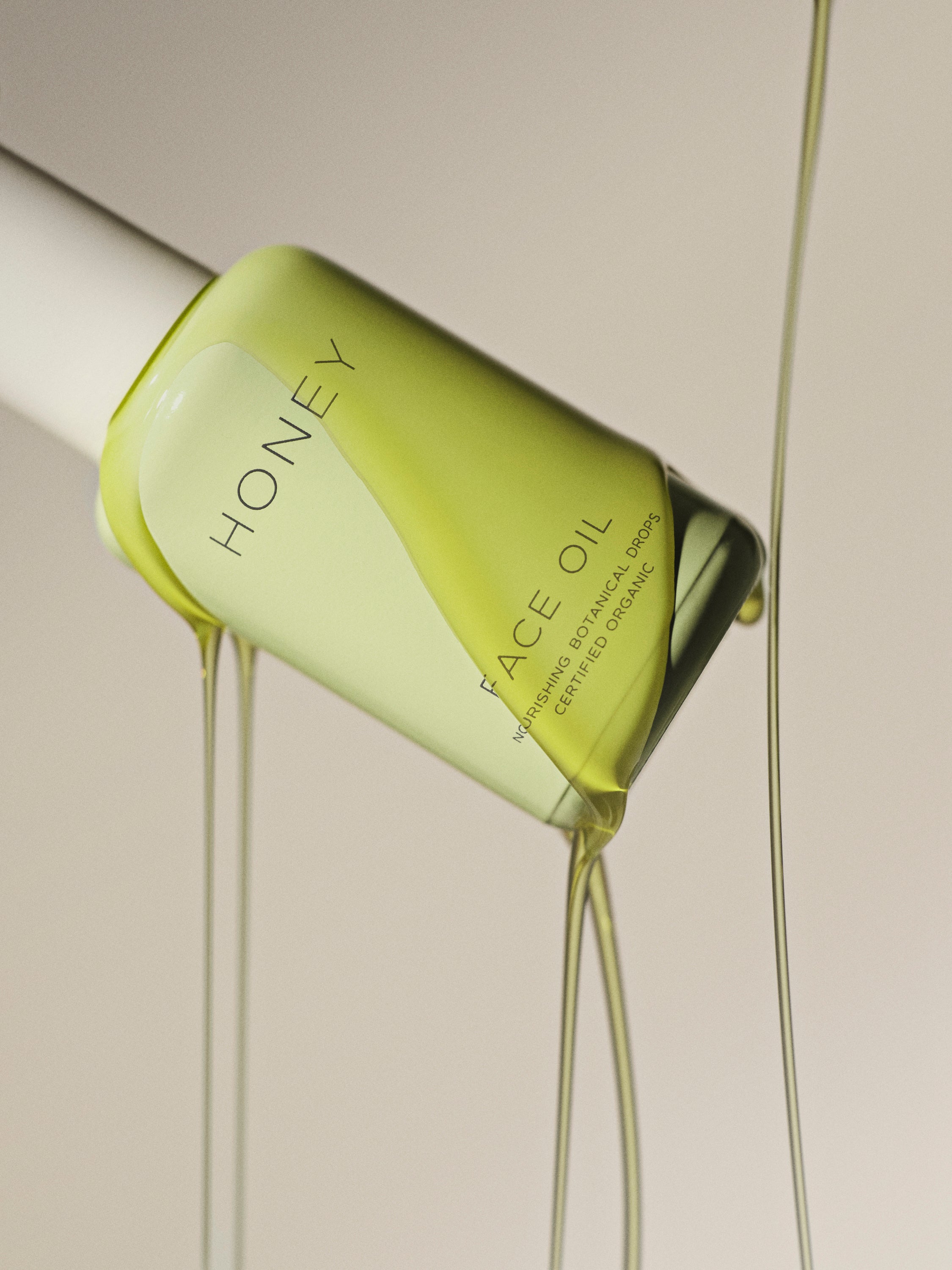 Natural fragrance-free face oil in green bottle with white cap with green botanical drops pouring over it