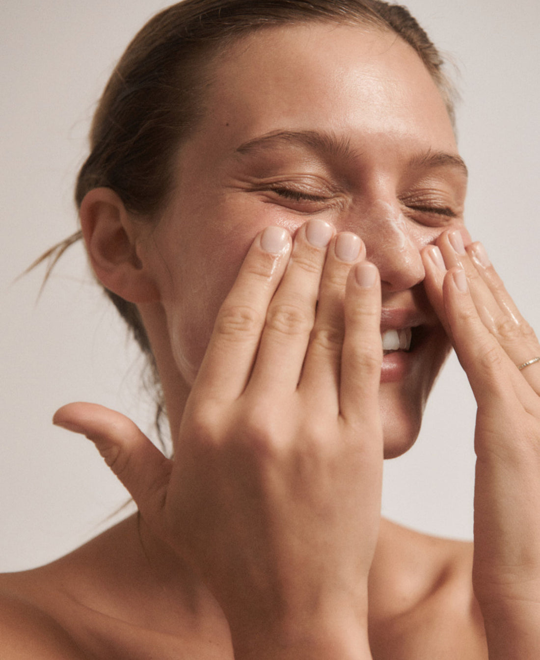 Woman putting natural fragrance-free everyday face cream on her face