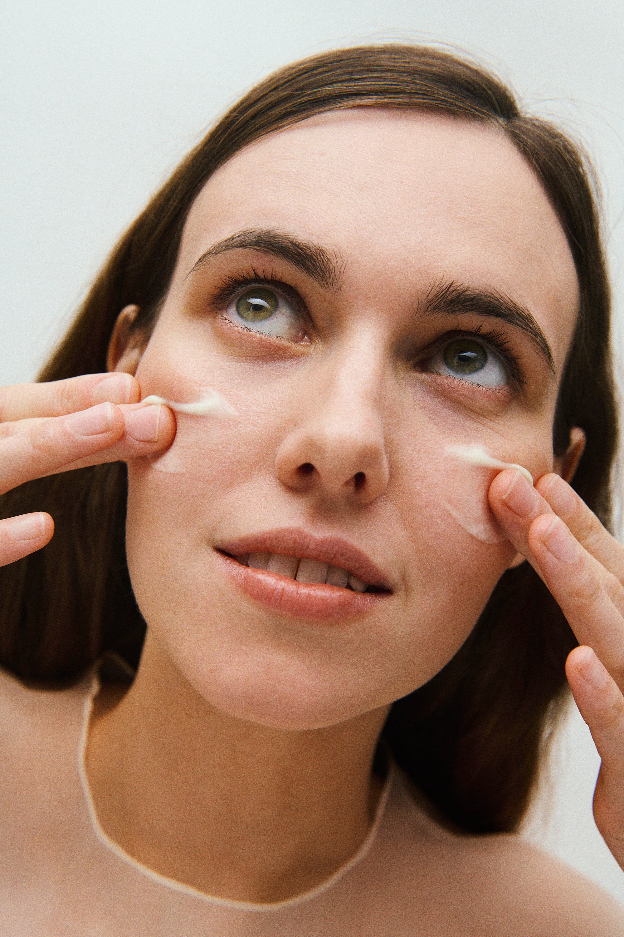 Woman with long dark hair putting fragrance-free double A vitamin serum clean on her face